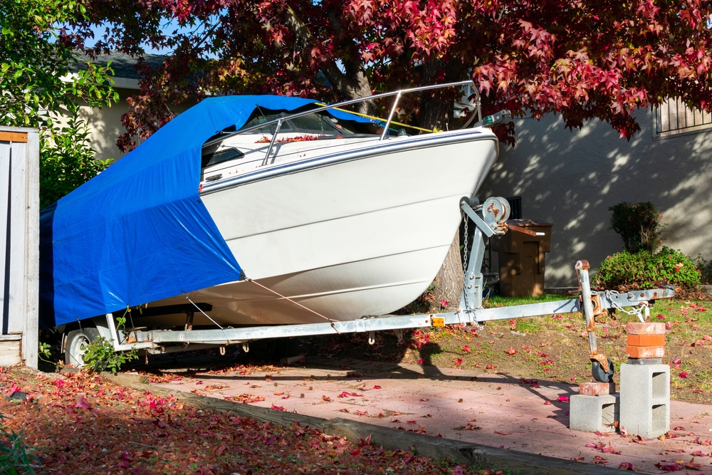 Recreational,boat,on,trailer,stored,on,driveway,of,residential,home.