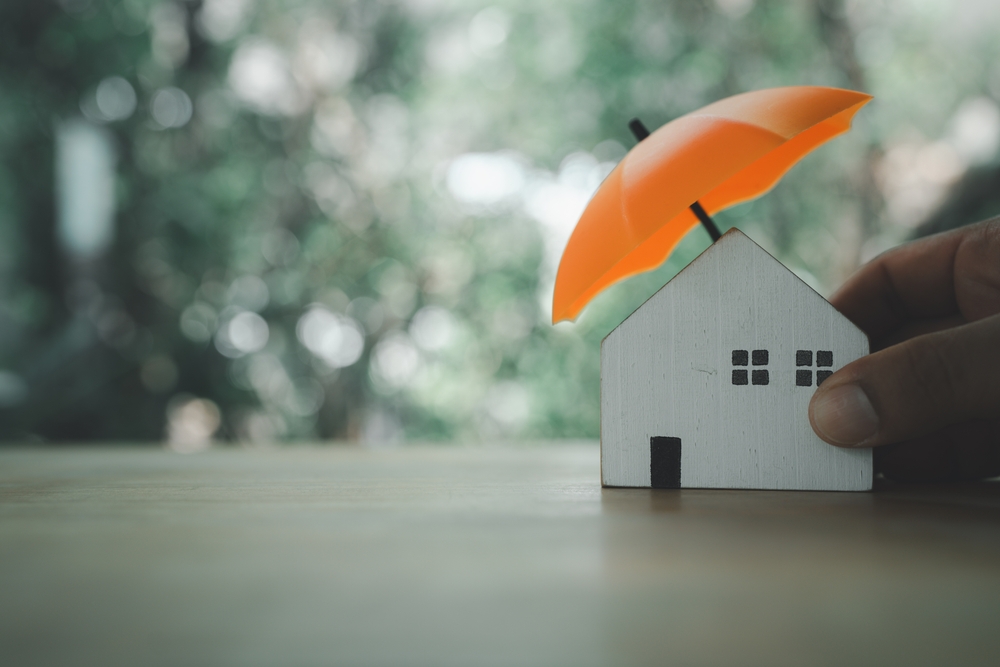 An,insurance,agent,is,holding,a,orange,umbrella,over,a